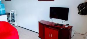uma sala de estar com televisão num armário vermelho em Chalé Sitio Miranda Sra Solange em Aratuba
