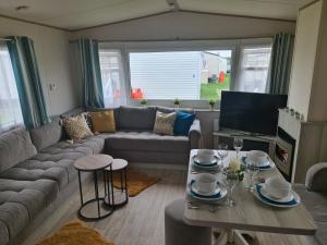 a living room with a couch and a table at Delux Caravan - Clacton-on-sea in Jaywick Sands