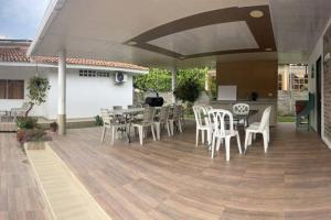 um pátio com cadeiras e mesas brancas e um piso de madeira em Finca y Piscina de Ensueño em El Cerrito