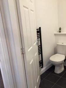 La salle de bains est pourvue de toilettes et d'une porte blanche. dans l'établissement LovelyHome 4 family& Contractors, à Killingbeck