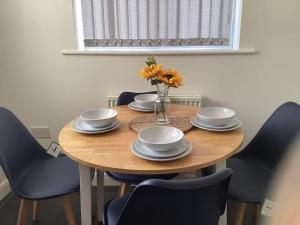 une table en bois avec des chaises et un vase de fleurs. dans l'établissement LovelyHome 4 family& Contractors, à Killingbeck