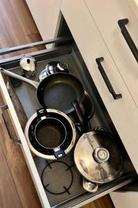 dos ollas y sartenes en un cajón en una cocina en white home near Linate en Segrate