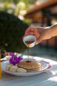 a person is pouring syrup onto a plate of pancakes at Hotel Villabosque Eco Boutique in Manuel Antonio