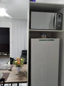 a microwave on top of a refrigerator next to a table at Apto Prático n.07 in Cascavel +10 photos