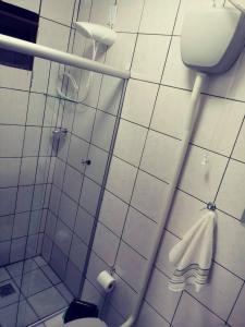 a white tiled bathroom with a toilet and a shower at Apto Prático n.07 in Cascavel