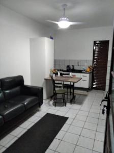 a living room with a black couch and a kitchen at Apto Prático n.07 in Cascavel
