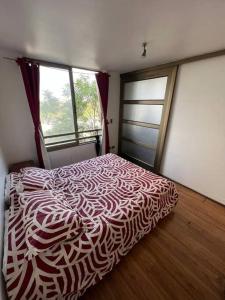 a bedroom with a bed with a red and white comforter at Departamento Central in Santiago