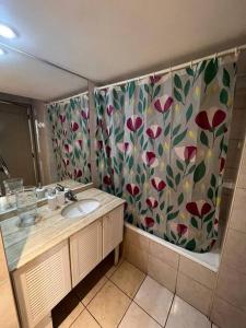 a bathroom with a sink and a shower curtain with flowers at Departamento Central in Santiago
