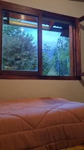a bedroom with a window with a bed and trees at HOSTEL EL LIMON in El Bolsón