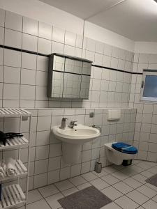 a white tiled bathroom with a sink and a toilet at Sunset Apartment mit Rheinblick in Urbar in Urbar-Mayen-Koblenz