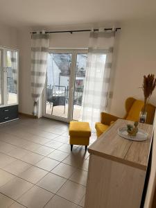 a living room with a table and a yellow chair at Sunset Apartment mit Rheinblick in Urbar in Urbar-Mayen-Koblenz