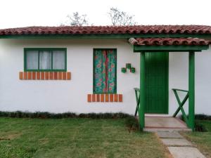 uma casa branca com uma porta verde e um quintal em Pouso Jambo Rosa em Valença