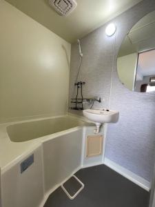 a bathroom with a sink and a tub and a mirror at InnCocoSumu？ - Vacation STAY 02654v in Kirishima