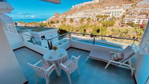 a balcony with a table and chairs and a view of a building at Nice flat with terrace in Puerto Rico in Puerto Rico de Gran Canaria