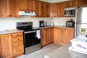 a kitchen with wooden cabinets and a black stove top oven at Beautiful Home 5 Minutes from Ottawa Airport in Ottawa