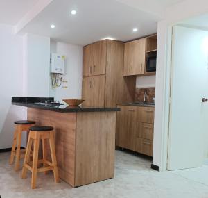 una cocina con armarios de madera y una barra con taburetes en Acogedor apartaestudio ubicado en Laureles, en Medellín