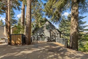 a house with a fence and trees in front of it at Quiet Tri-Level Chalet w/Breathtaking Views in Lake Arrowhead
