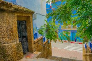 ein blaues Gebäude mit einer Tür in einer Straße in der Unterkunft Lala Zohra in Chefchaouen