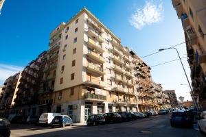 een hoog gebouw in een straat met geparkeerde auto's bij Casamu' Management Apartment in Palermo