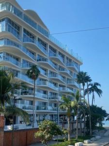 een groot appartementencomplex met palmbomen voor de oceaan bij Apartamento en Bucerías frente al mar, condominio Tayau in Bucerías