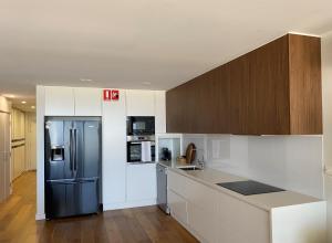 a kitchen with a black refrigerator and white cabinets at Tranquillity On The Promenade in Batemans Bay