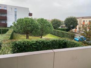 Blick auf einen Garten mit Bäumen und ein Gebäude in der Unterkunft Chambre chez lhabitant in Toulouse