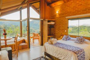a bedroom with a bed and a large window at Pousada Ho'oponopono Chalets & Wine in Sapucaí-Mirim