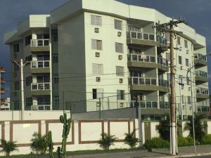ein hohes weißes Gebäude mit Balkonen in der Unterkunft Espaçoso apê 3 quartos à beira da Praia do Forte com piscina e sauna in Cabo Frio