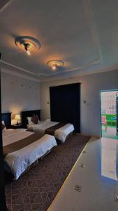 a hotel room with two beds and a large window at هتان السودة Hattan Al-Sodah in Suda