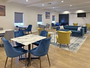 - une salle d'attente avec des tables, des chaises et un canapé dans l'établissement Clarion Pointe Winslow I-40, à Winslow