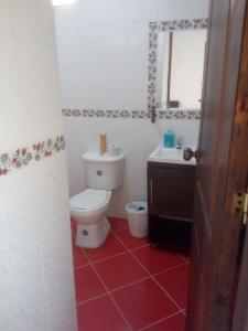 La salle de bains est pourvue de toilettes blanches et d'un sol rouge. dans l'établissement Hotel Barajas, à Jardín