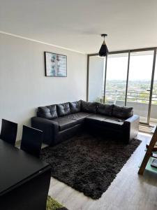 sala de estar con sofá de cuero negro y mesa en Apartamento en Concepción, en Concepción