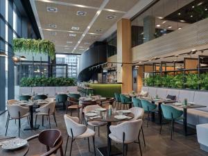 a restaurant with tables and chairs and plants at Radisson Hotel Budapest BudaPart in Budapest
