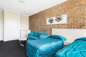 a bedroom with two beds and a brick wall at Marion Motel and Apartments in Adelaide