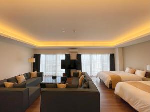 um quarto de hotel com duas camas e uma sala de estar em ＆Monde. Okinawa Arena Condominium em Okinawa