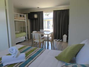 a bedroom with a bed and a dining room with a table at Tasman Holiday Parks - Merimbula in Merimbula