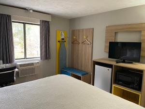 ein Hotelzimmer mit einem Bett und einem Flachbild-TV in der Unterkunft Days Inn by Wyndham Warrensburg in Warrensburg