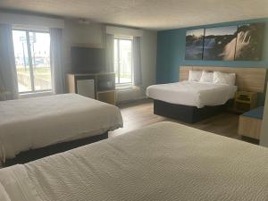 a hotel room with two beds and two windows at Days Inn by Wyndham Warrensburg in Warrensburg