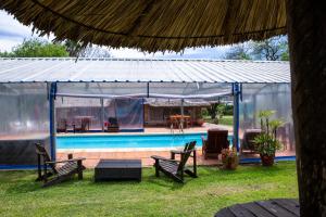 a pavilion with a pool and a table and chairs at Posada de Campo San Cono in Mercedes