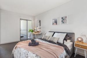 un dormitorio con una cama grande con un gato sentado en ella en U8/51 Bright 3 bd city, en Perth