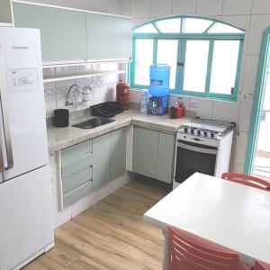 uma cozinha com armários brancos, um lavatório e um fogão em Casa pertinho da praia com piscina e churrasqueira em Peruíbe