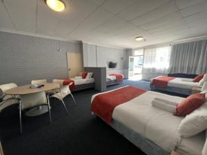 ein Hotelzimmer mit 2 Betten und einem Tisch in der Unterkunft Princes Lodge Motel in Adelaide