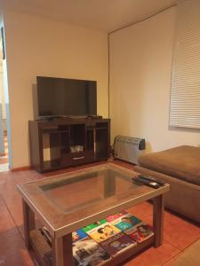 ein Wohnzimmer mit einem TV und einem Couchtisch in der Unterkunft CASA COMPLETA 2 PLANTAS CON EXTRAORDINARIA VISTA AL CANAL BEAGLE CENTRICA 4pax in Ushuaia