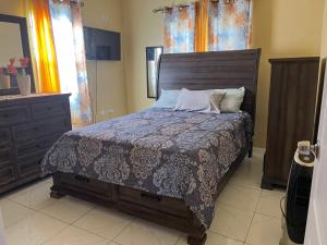 a bedroom with a bed and a dresser and window at Finest Accommodation Phoenix Park Lot 1317 Phase 4 Portmore St Catherine in Portmore