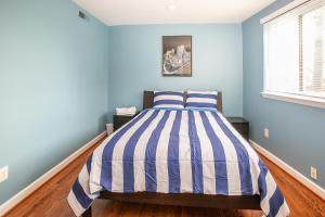 a blue bedroom with a bed with a striped comforter at Comfy and Cozy-Min to National Mall Great Location in Arlington
