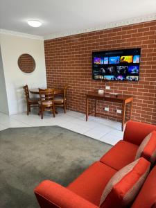a living room with a red couch and a tv on a brick wall at The Roseville Apartments in Tamworth