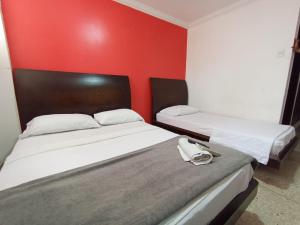 two beds in a room with a red wall at HOTEL AVANTY INN in Barranquilla