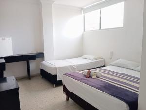 a bedroom with two beds and a desk and a piano at HOTEL AVANTY INN in Barranquilla
