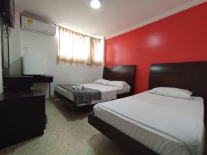 a hotel room with two beds and a red wall at HOTEL AVANTY INN in Barranquilla