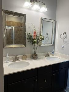 Baño con 2 lavabos y un jarrón de flores en The Birch Bungalow, en Charlotte